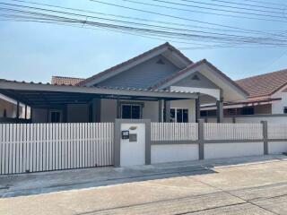 Front view of a single-story residential house with a white fence