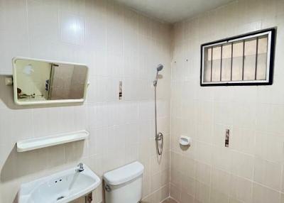 Compact bathroom with white ceramic fixtures and tiled walls