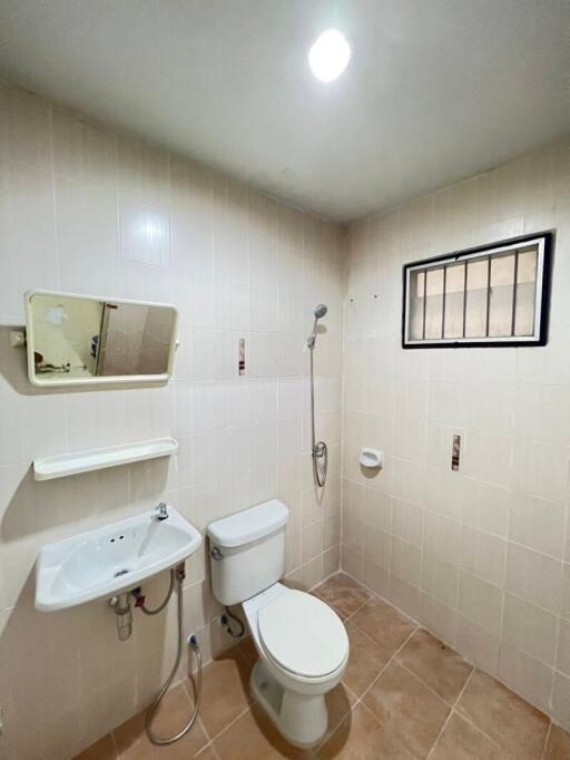 Compact bathroom with white ceramic fixtures and tiled walls