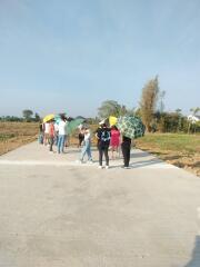 Group of people with umbrellas standing on a concrete pathway in a developing outdoor area