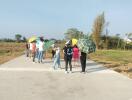 Group of people with umbrellas standing on a concrete pathway in a developing outdoor area