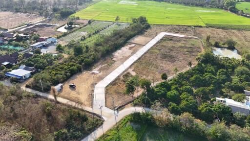 Aerial view of a large vacant land plot with nearby housing and agricultural fields