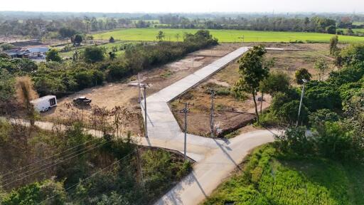 Aerial view of an open land property with access roads and surrounding greenery