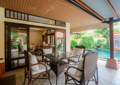 Covered patio area with outdoor dining set near a pool