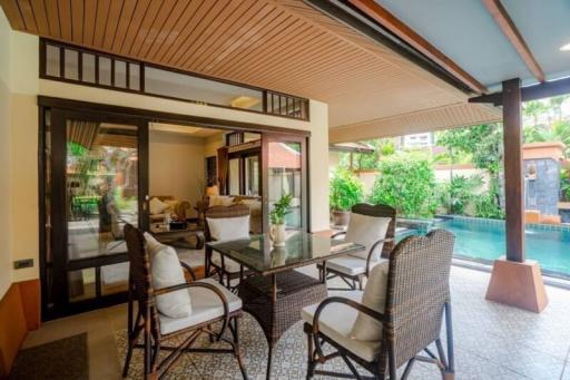 Covered patio area with outdoor dining set near a pool