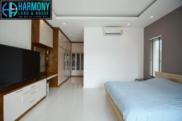 Spacious modern bedroom with large bed and entertainment unit