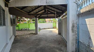 Spacious covered carport area with concrete flooring and surrounding fence