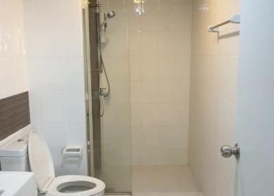 Modern white tiled bathroom with glass shower and toilet