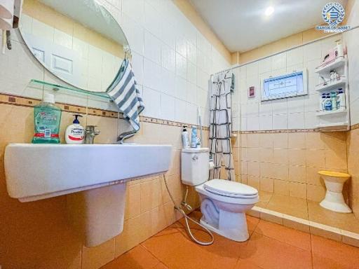 Clean tiled bathroom with sink, toilet, and accessories