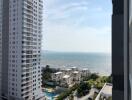 Seaside view from a high-rise apartment balcony showing nearby buildings and the ocean