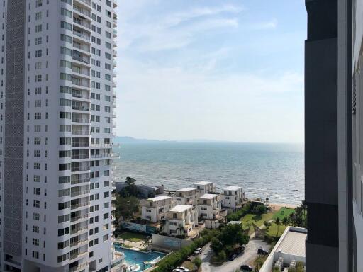 Seaside view from a high-rise apartment balcony showing nearby buildings and the ocean