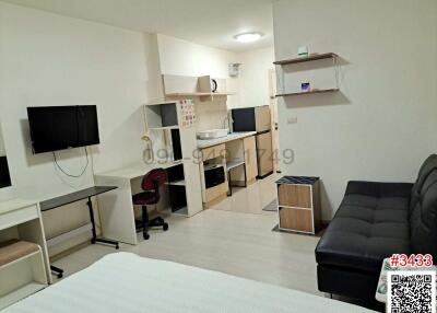 Compact and well-equipped studio apartment interior with integrated living, sleeping, and kitchen area