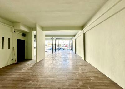 Spacious open-plan interior of a building with large windows and hardwood floors