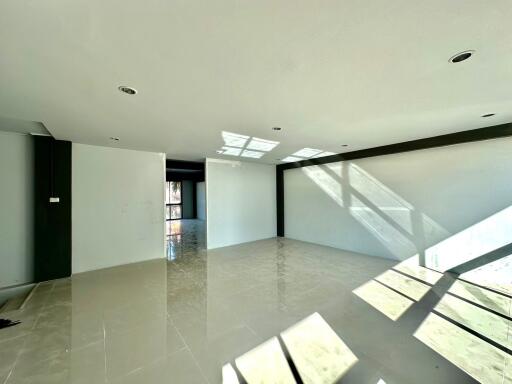 Spacious and bright unfurnished living room with large windows and glossy tiled flooring