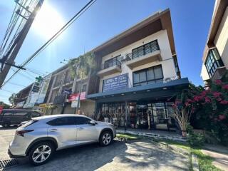 Modern multi-level commercial building with retail space on ground floor against a clear blue sky