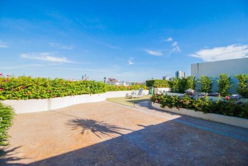 Spacious terrace with garden planters and outdoor seating under a clear blue sky