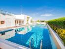 Bright and luxurious outdoor pool with white building and clear blue sky