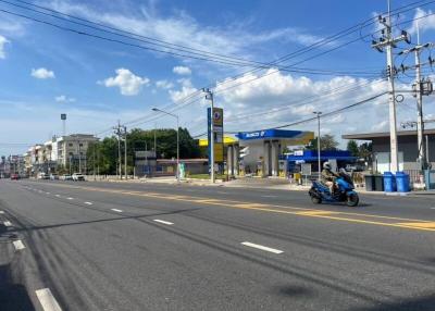 A wide street view with a gas station and buildings under a clear blue sky