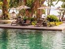 Luxurious resort style pool area with sun loungers and umbrellas by the water