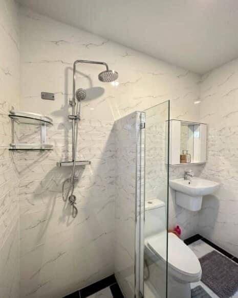 Modern bathroom with marble tiles, glass shower, and wall-mounted toilet