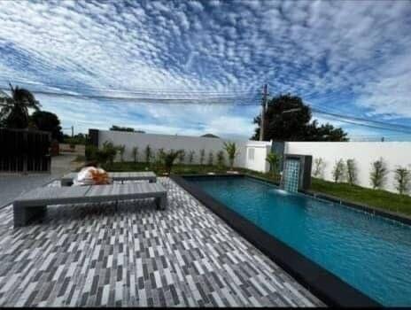 Spacious outdoor swimming pool with lounging area under a dramatic sky