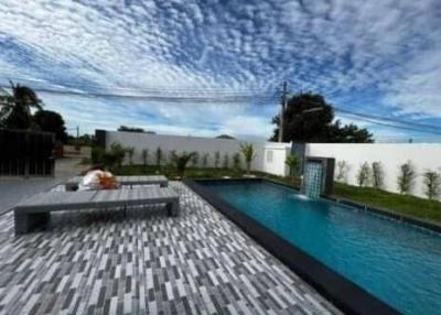 Spacious outdoor swimming pool with lounging area under a dramatic sky