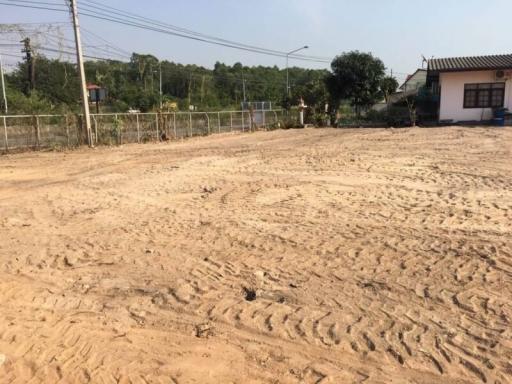 Vacant land ready for construction with fence and nearby buildings