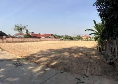 Spacious empty plot of land with clear skies and surrounding residential structures