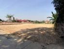 Spacious empty plot of land with clear skies and surrounding residential structures