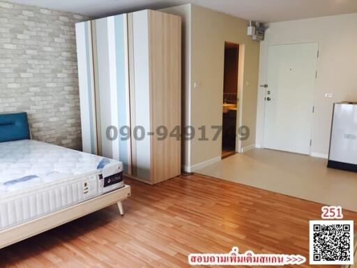 Spacious bedroom with wooden flooring and brick accent wall