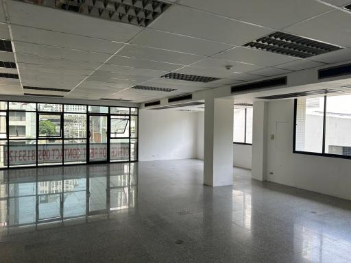 Spacious empty commercial space with large windows and reflective flooring