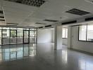 Spacious empty commercial space with large windows and reflective flooring
