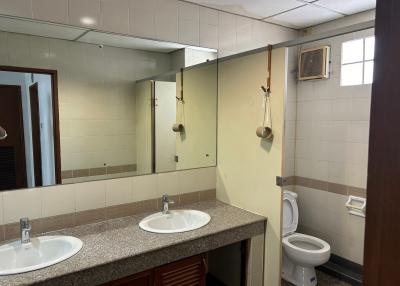 Spacious bathroom with double vanity sinks, large mirror, and toilet