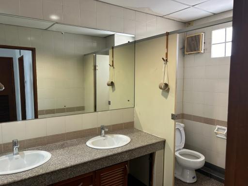 Spacious bathroom with double vanity sinks, large mirror, and toilet