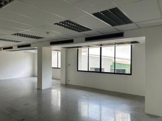 Spacious unfurnished open-plan office space with large windows and tiled flooring