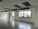 Spacious unfurnished open-plan office space with large windows and tiled flooring