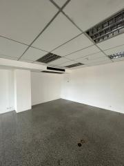 Empty interior space of a building with tiled flooring and drop ceiling