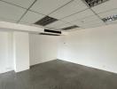 Empty interior space of a building with tiled flooring and drop ceiling