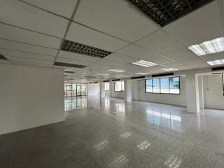 Spacious empty commercial office space with large windows and terrazzo flooring