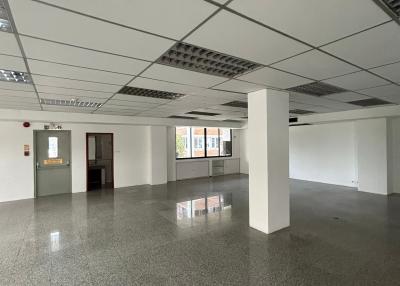 Empty commercial space with tiled flooring and suspended ceiling