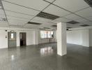 Empty commercial space with tiled flooring and suspended ceiling