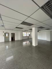 Empty commercial space with tiled flooring and suspended ceiling