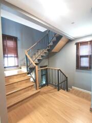 Modern staircase with wooden steps and metal railing in a well-lit home interior