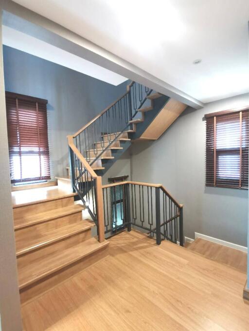 Modern staircase with wooden steps and metal railing in a well-lit home interior