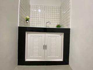 Modern bathroom sink with white cabinet and black countertop