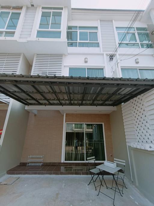 Exterior view of a modern townhouse with patio furniture