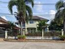 Suburban two-story house with gated fence and palm trees