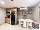 Modern kitchen with wooden cabinets, white dining table, and stainless-steel refrigerator