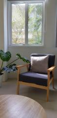 Cozy living room corner with a modern armchair, round wooden table, and a view of the outside through a window