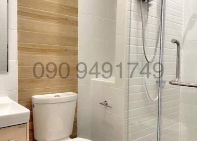 Modern bathroom interior with a white ceramic toilet, electric shower unit, and wooden paneling